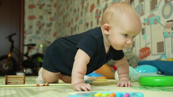 Evde, oyun odasında küçük bir çocuk dört ayak üstünde sürünmeyi ve ayağa kalkmayı öğreniyor. Bir seneye kadar bir bebeğin boş zamanı ve gelişimi. Yüksek kalite 4k görüntü - Video, Çekim