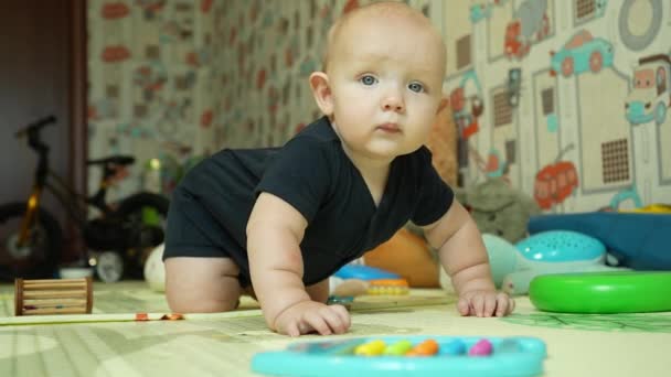Oyun odasında küçük bir çocuk dört ayak üstünde sallanıyor ve gülümsüyor. Bir seneye kadar bir bebeğin boş zamanı ve gelişimi. Yüksek kalite 4k görüntü - Video, Çekim