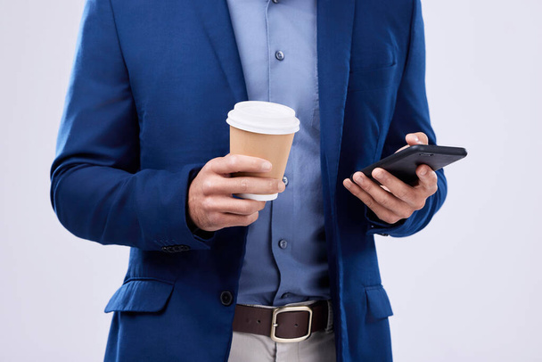 Phone, coffee and closeup of businessman hands in studio typing message on social media, mobile app or the internet. Technology, cappuccino and lawyer scroll online with cellphone by white background. - Photo, Image