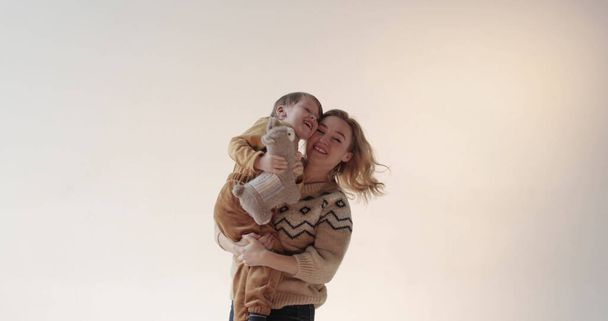 Een moeder met haar zoon in haar armen in de studio. Gelukkige moeder van een mooie zoon. Portret van moeder en zoon in studio. - Foto, afbeelding