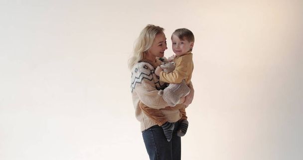 Une mère avec son fils dans les bras dans le studio. Bonne mère d'un beau fils. Portrait de mère et fils en studio. - Photo, image