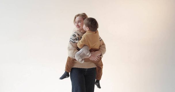 A mother with her son in her arms in the studio. Happy mother of a beautiful son. Portrait of mother and son in studio. - Photo, Image