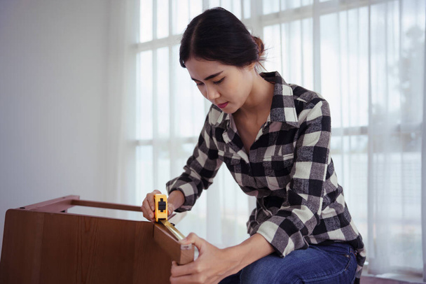 Жінки вимірюють довжину стільця з мірною стрічкою під час складання та ремонту меблів стільців. - Фото, зображення