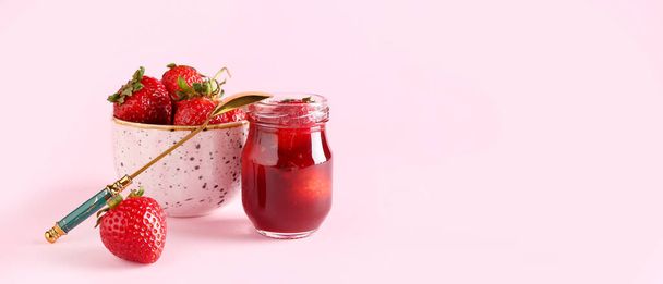 Jar of sweet strawberry jam and fresh berries in bowl on pink background with space for text - Photo, Image