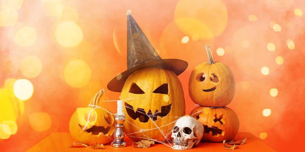 Dynie Jack-O-Lantern, świeca, czaszka i spadające liście na pomarańczowym tle - Zdjęcie, obraz