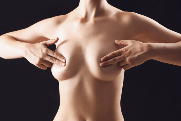 Jovem nua cobrindo seu peito no fundo preto - Foto, Imagem