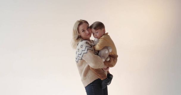 スタジオで息子を抱えた母親. 美しい息子の幸せな母親. スタジオで母と息子の肖像画. - 写真・画像