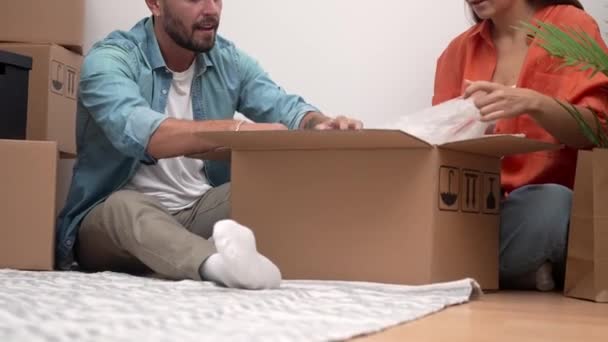 Cheerful couple unpacks moving boxes, creating their dream home. The glow of a new beginning, joy in the simple moments - Footage, Video