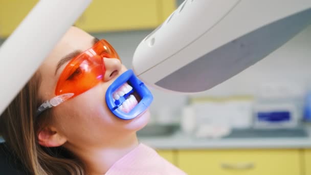 Clareamento dos dentes na clínica dentária privada. Paciente em óculos de proteção ocular de UV se prepara para o procedimento de clareamento com o médico na clínica odontológica - Filmagem, Vídeo