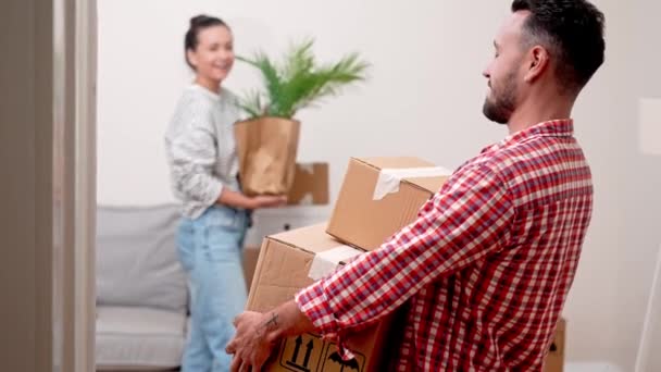 Propiedad de la casa: sonrisas de pareja brillan mientras empacan cajas durante el traslado a su casa hipotecada - Metraje, vídeo