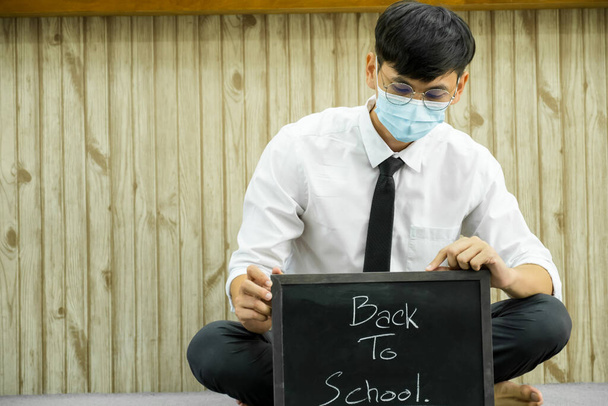 Férfi ázsiai diák ül vissza az iskolai táblát az egyetemi osztályteremben. - Fotó, kép