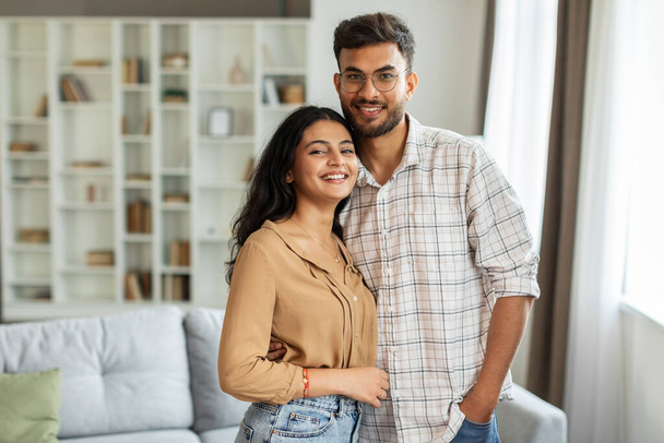 Muotokuva nuorten romanttinen intialainen pari syleilee ja hymyilee, poseeraa olohuoneessa sisustus, nauttia aikaa yhdessä, vapaata tilaa - Valokuva, kuva