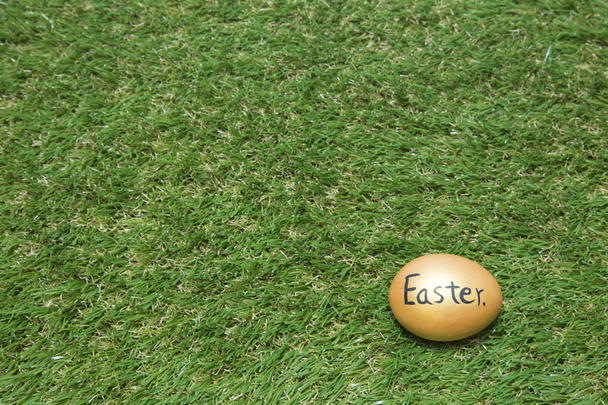 Gold easter egg on green grass - Фото, изображение
