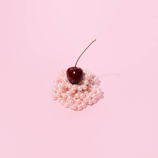 Pastel roze stapel parelkralen, een frisse sappige kers op de top, creatieve esthetische fruitige dessert idee. Zomer modetrends.  - Foto, afbeelding