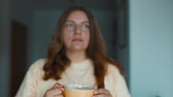 Közel a vonzó, békés, álmodozó nő tartó csésze élvezze tea vagy kávé ital reggeli élénkítő kávé ital, miközben ül a teraszon.  - Felvétel, videó