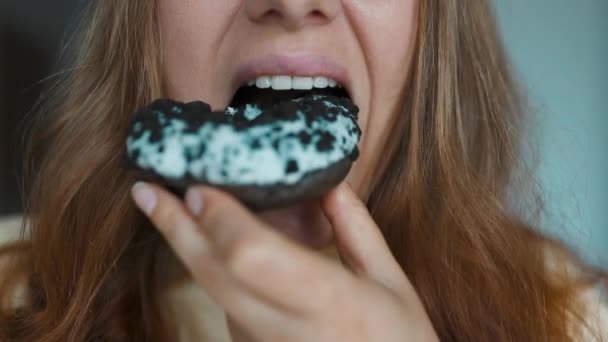 Close up portrait of a hungry 30s woman eating donuts with white frosting. Eating donut when takeout and delivery. Fast food takeaway back home. High quality FullHD footage. High quality FullHD - Footage, Video