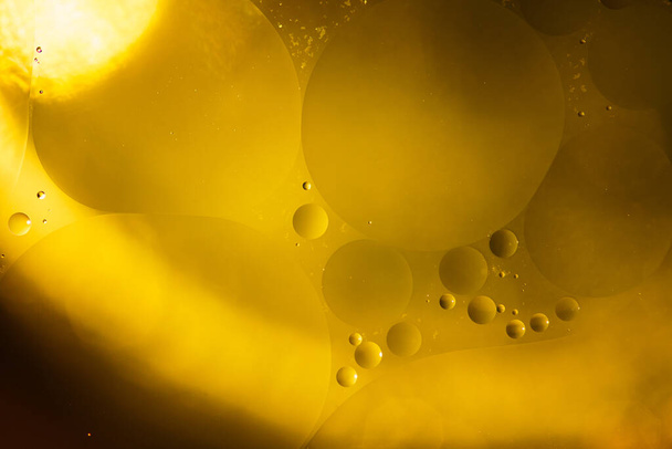Gele olie bellen op water, bakolie achtergrond. - Foto, afbeelding