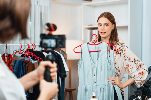 Woman influencer shoot live streaming vlog video review clothes utmost social media or blog. Happy young girl with apparel studio lighting for marketing recording session broadcasting online. - Photo, Image
