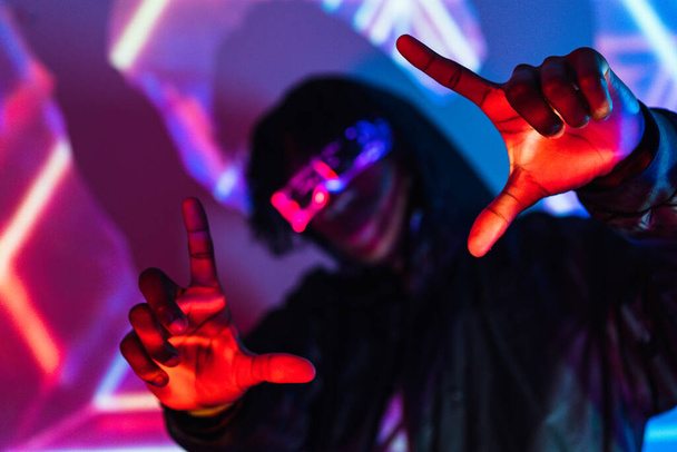 Studio portrait with purple and blue neon lights of a futuristic man picturing the future gesturing with hands - Foto, Bild