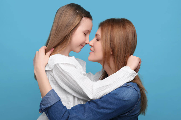Portrait of mother and her cute daughter on light blue background - Foto, immagini