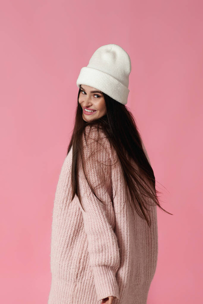 pretty young woman in white hat, pink sweater looking at the camera on pastel pink background. - Фото, зображення
