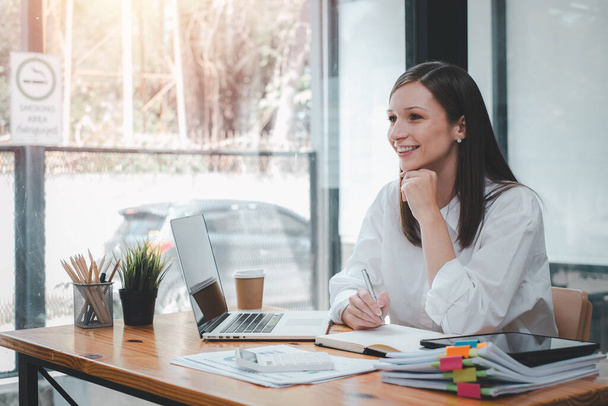 Portrait of young smiling woman looking at camera. Happy girl sitting in creative office. Successful businesswoman standing in office with copy space. - Photo, Image