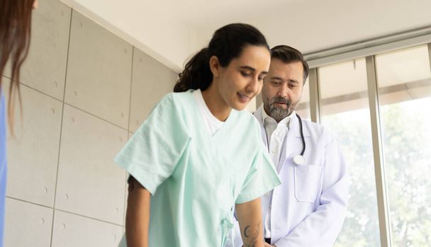 Dokter en fysiotherapeut doen een revalidatie herstel voor Spaanse patiënt meisje. Gezondheidszorg en medische dienst in het ziekenhuis. Het medisch onderzoek en de therapie voor lichamelijk letsel. - Foto, afbeelding