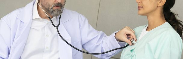 Kaukasischer Arzt diagnostiziert Ursachenforschung mittels Stethoskop bei hispanischen Patientinnen. Die medizinische Gesundheitsprüfung und der Check-up mit dem ärztlichen Konzept. - Foto, Bild