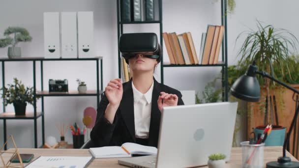 Деловая женщина, использующая футуристическую технологию виртуальной реальности, шлем гарнитуры VR для моделирования 3D 360 видео на современном офисном рабочем месте. Взволнованная девушка-фрилансер. Удаленная работа в режиме онлайн - Кадры, видео