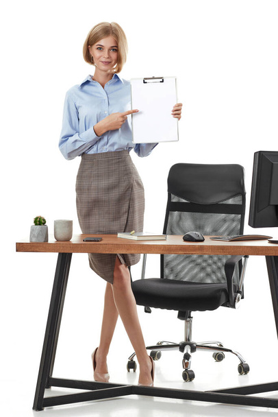 positive business woman in formal wear showing empty clipboard in office - Фото, зображення