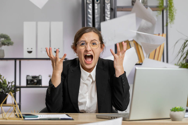 Stressed young business woman working looking at unpaid bank debt bills, doing paperwork, planning budget, calculate finances mortgage payments at office. Displeased freelancer girl throws paper bills - Photo, Image