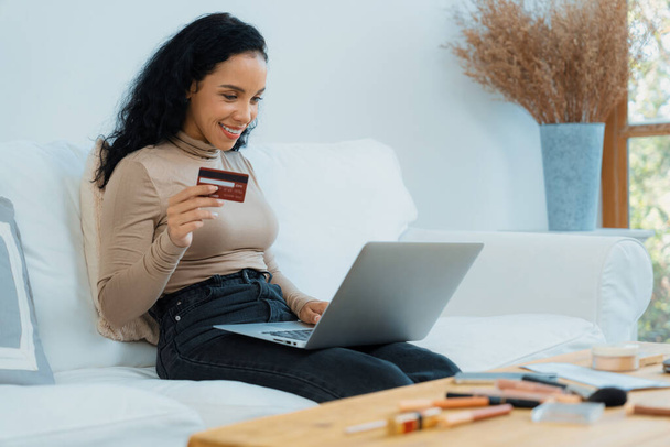 Junge glückliche Frau kauft Produkt durch Online-Shopping zu Hause, während die Bestellung von Artikeln aus dem Internet mit Kreditkarte Online-Zahlungssystem durch entscheidende Cyber-Sicherheit von Online-Shop-Plattform geschützt - Foto, Bild