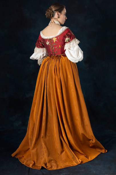 Αναγέννηση, Τυδώρ, Γεωργιανή ή γυναίκα υψηλής φαντασίας που φοράει κεντημένο μπούστο με λινό φανελάκι και μακριά φούστα δύο τεμαχίων σε φόντο στούντιο - Φωτογραφία, εικόνα