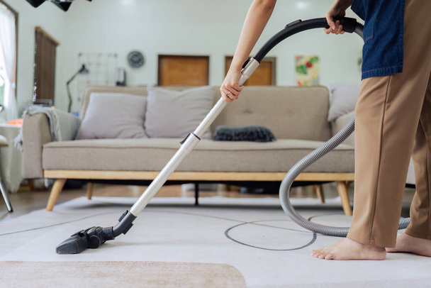 Mooi jong meisje huishoudster schoner dragen schort en stofzuigen rommelige vuile vloer voor huishoudelijk werk en klusjes in huis. - Foto, afbeelding
