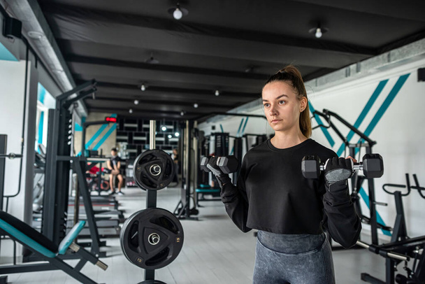 close-up jonge vrouw traint spieren op fitnessapparatuur in de sportschool. sport concept. fitness manier van leven en mensen. - Foto, afbeelding