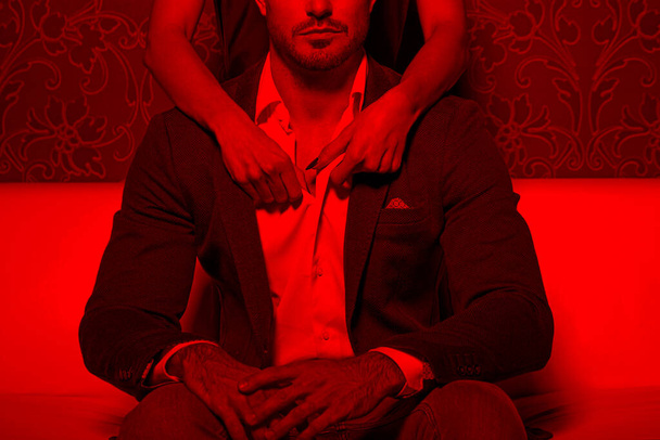 kobieta ręce rozbierać mężczyzna koszula od tyłu w czerwonym świetle, vintage pokój - Zdjęcie, obraz