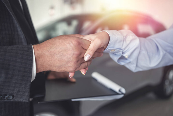 Успешная сделка в выставочном зале - продавец и клиент пожимают друг другу руки, заканчивая - Фото, изображение