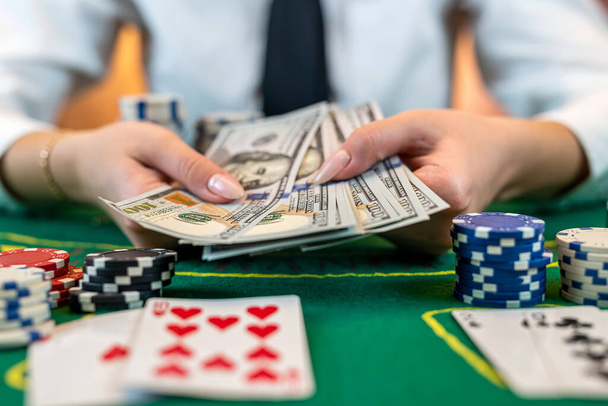 女性プレーヤーはお金のためのチップをカウントし、カジノでポーカーをプレイしながら賭けを上げる。ギャンブルの概念。女とポーカーだ。隔離された - 写真・画像