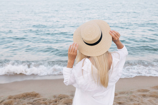 Досить струнка засмагла блондинка стильна жінка в солом'яному капелюсі позує на райському тропічному пляжі. - Фото, зображення
