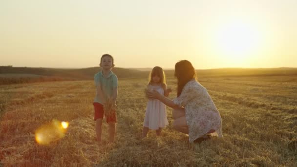 母親と一緒にいる陽気な子供たちは,干し草を投げ,喜び,笑う. 農場で幸せな家族が集まってくる. 高品質の4k映像 - 映像、動画
