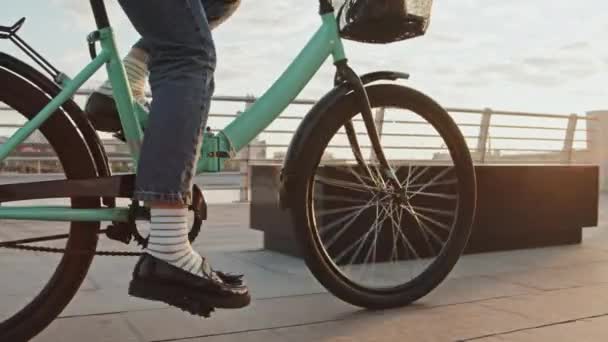 Tiro de seguimiento de sección baja de una mujer irreconocible que usa jeans, mocasines y calcetines a rayas en bicicleta por la mañana. - Imágenes, Vídeo