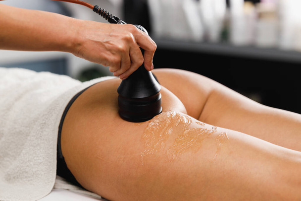 Shot of an unrecognizable woman getting an anti cellulite massage at the beauty salon. She have a vacuum treatment to fat reduction. - Photo, Image