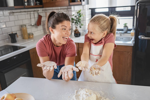 happy mother and daughter having fun with flour together at home  - Photo, Image