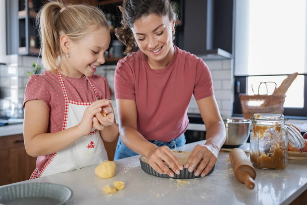 happy mother and daughter preparing pie together in kitchen - Photo, Image