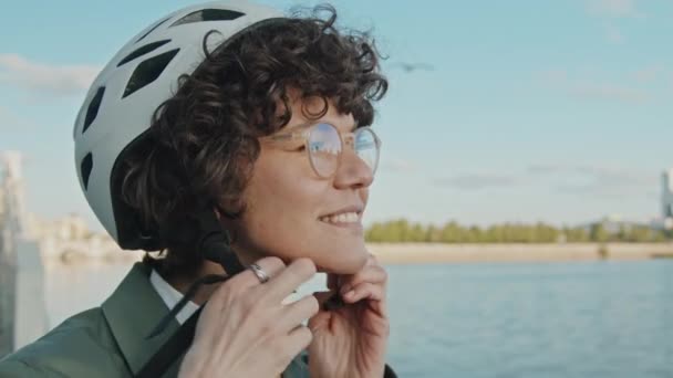 Lähikuva muotokuva iloinen valkoihoinen nainen kihara tukka silmälasit ottaa pois polkupyörän kypärä - Materiaali, video