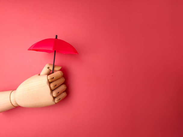 Fa kéz kezében piros esernyő egy piros háttér másolási hely. - Fotó, kép