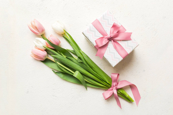 Flores de tulipas rosa e presente ou caixa de presente no fundo da mesa colorida. Dia das Mães, Aniversário, Dia das Mulheres, conceito de celebração. Espaço para a vista superior do texto. - Foto, Imagem