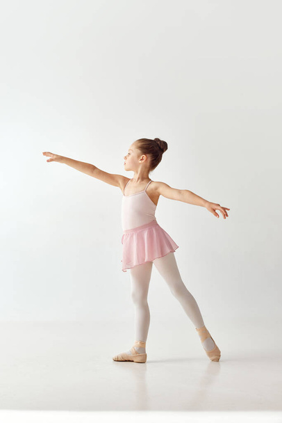 Retrato de pequeña bailarina preescolar adorable niña bailarina en vestido de ballet tutú rosa legging blanco de pie posando sobre fondo blanco. Concepto de belleza, moda, hobby, expresión personal, danza. - Foto, imagen