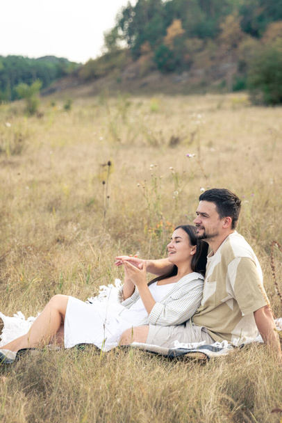 Gelukkig getrouwde man en vrouw op een date ontspannen in een veld in de zomer, quality time together, nauwe relatie, romantiek in het huwelijk. - Foto, afbeelding