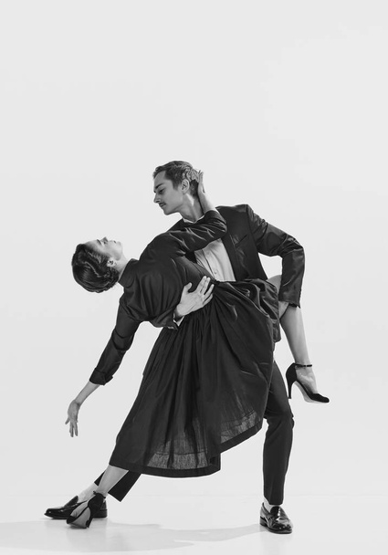 Elegancia a mozgásban. Fekete-fehér. Gyönyörű pár, férfi és nő elegáns ruhában táncolnak. Fogalma hobbi, retro tánc, vintage stílus, koreográfia, szépség. Monokróm művészet. Hirdetés - Fotó, kép